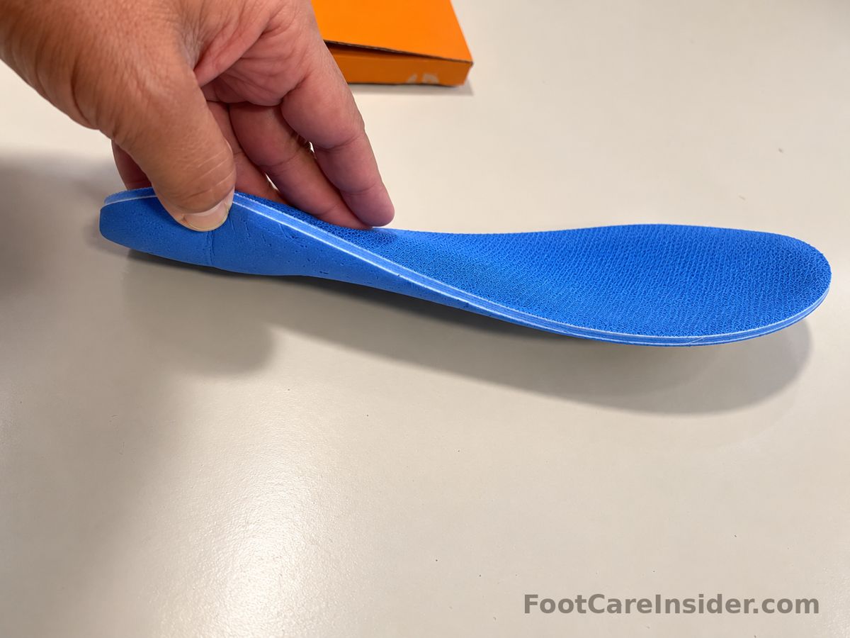 Hand bending a blue insole on a cream surface