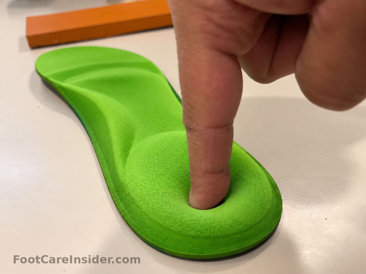 Finger pressing into a green cushioned insole