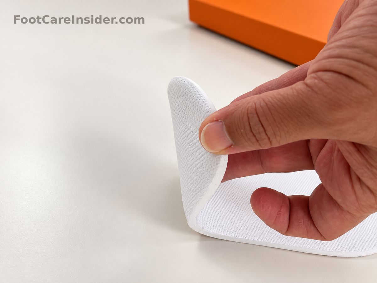 Hand bending a white flexible insole