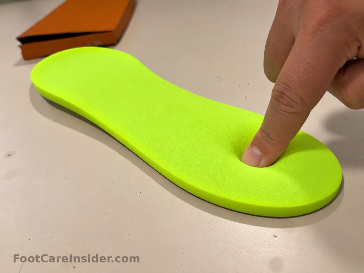 Finger pressing into a bright green-yellow foam insole