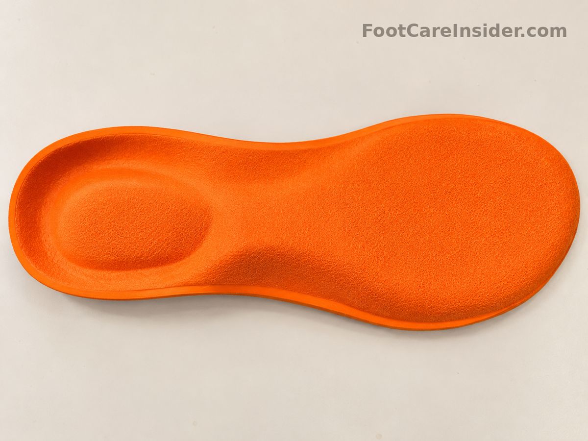 Orange contoured insole on a cream surface